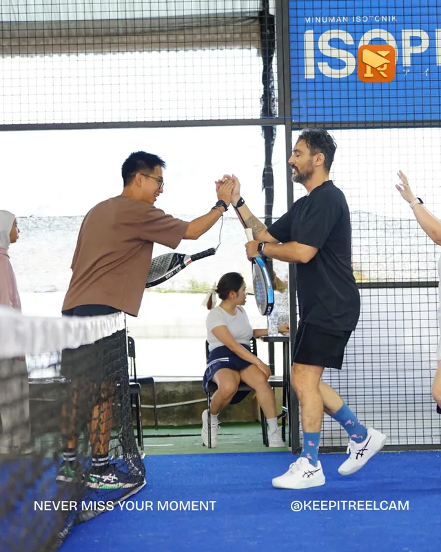Two padel players greet each other at the net.