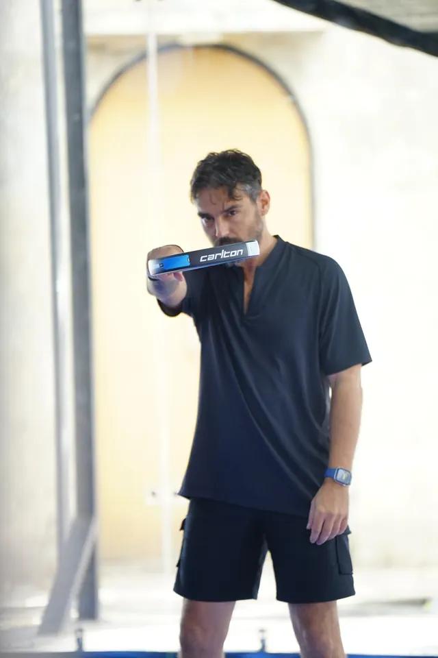 A padel player holds his racket up in front of him.